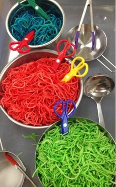 several bowls filled with different colored noodles and spoons on top of a metal tray