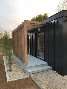 a small black building sitting in the middle of a field next to a tree and walkway