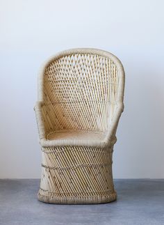 a white wicker chair sitting on top of a cement floor next to a wall