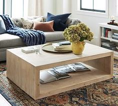 a living room with a couch, coffee table and bookshelf in the corner