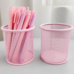 two pink plastic cups with different colored straws in them sitting on a table next to each other