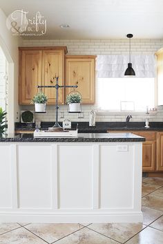 a kitchen with wooden cabinets and marble counter tops, along with potted plants on the island