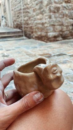 a person holding a small ceramic elephant ring in their right hand, with the other hand on it's hip