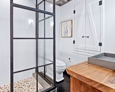 a bathroom with a toilet, sink and glass partitions in it's walls