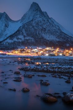 the mountain is covered in snow and lit up at night with lights shining on it