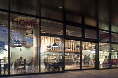 the front window of a restaurant with tables and chairs in it at night, lit up by street lights