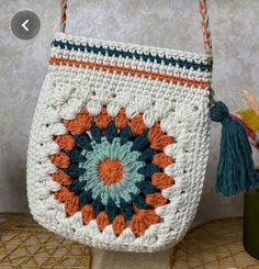 a crocheted bag with tassels hanging from it