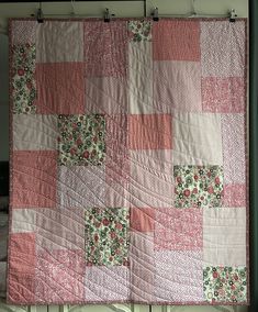 a pink and white quilt hanging on the wall