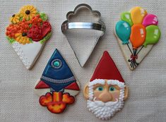 several decorated cookies are sitting on a table with balloons and flowers in the shape of gnomes