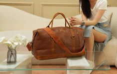 Discover unparalleled elegance with the FR Fashion Co. Leather Travel Duffel Bag. Crafted from premium vegan leather, this duffel is your ultimate companion for short trips, offering both unmatched style and substantial space. Its vintage brown accents and red lining enhance its aesthetic appeal, making it a sophisticated choice for any traveler. Key Features: Material: High-quality vegan leather with vintage brown accents and red lining for a classic look. Spacious Capacity: Dimensions of 20x15x9 inches provide ample space for all your essentials, ideal for weekend or 4-5 day trips. Versatility: Perfect as a carry-on, gym, sport, or overnight travel bag, meeting most airline requirements. Functional Design: Features a detachable & adjustable shoulder strap made of heavy-duty canvas and du Travel Duffel Bag, Overnight Travel Bag, Weekend Travel Bags, Travel Duffel, Duffel Bag Travel, Short Trip, Leather Travel, Free Bag, Vintage Brown