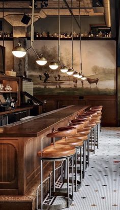 an empty bar with stools and lights hanging from the ceiling in front of it