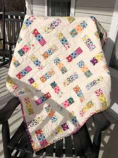 a white quilt sitting on top of a wooden chair in front of a porch door