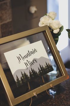 there is a sign that says mountain river in front of a vase with white flowers