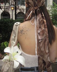 the back of a woman's neck with a flower in her left hand and a ribbon tied to it