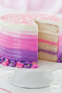 a white cake with pink and purple frosting on it's side sitting on a plate