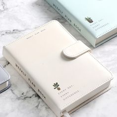 three different colored notebooks sitting on top of a marble counter next to each other