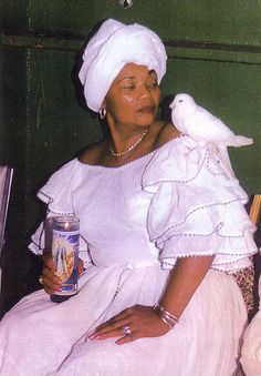 a woman sitting on a chair holding a can and a bird perched on her shoulder