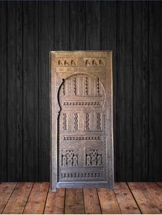 an old metal door on a wooden floor in front of a black wall with wood planks