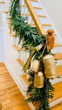 some gold bells are hanging from the banisters and greenery on the stairs