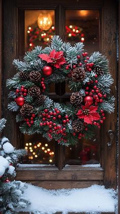 a christmas wreath with poinsettis and pine cones in front of a door