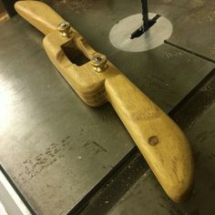 a wooden skateboard sitting on top of a piece of metal in a shop or workshop