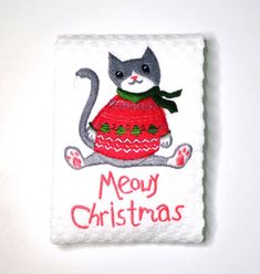 a white towel with a cat wearing a red sweater and merry christmas written on it