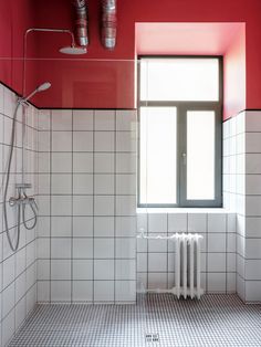 a bathroom with red walls and white tile flooring next to a radiator