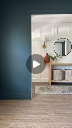 an open door leading to a bathroom with blue walls and wood floors, in front of a mirror on the wall