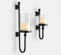 two candle holders are on the wall next to each other, one is black and the other is white