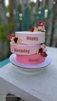 three tiered cake sitting on top of a white plate covered in pink frosting