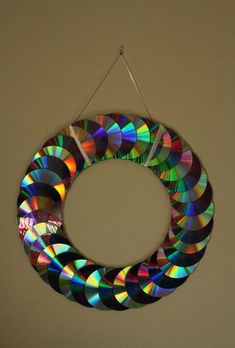 a multicolored circular hanging decoration made out of cd's on a wall