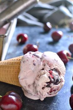 a scoop of ice cream with cherries on the table next to an ice cream cone