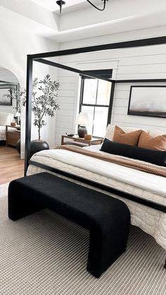 a bedroom with a bed, mirror and ottoman on the floor in front of it