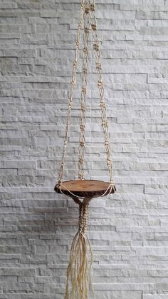 a bird bath hanging from a rope on a brick wall