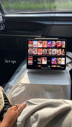 a laptop computer sitting on top of a bed next to a person in a car