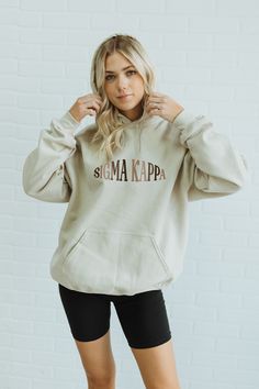 a woman wearing a cream sweatshirt with the words mama kapp on it and black shorts