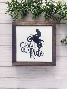 a wooden frame with a sign that says crawl the walk ride on it and a man riding a dirt bike