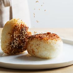 two pieces of food on a plate with sesame seeds sprinkled over them and being tossed in the air