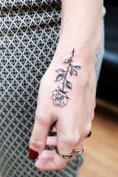 a woman's hand with a flower tattoo on it