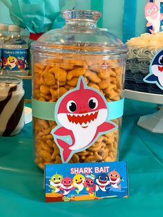 a table topped with a jar filled with cookies next to a cake covered in candy