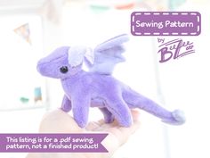 a hand holding a purple stuffed animal with wings on it's back and the caption saying sewing pattern by blythe