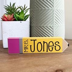 a pencil sitting on top of a wooden table next to a potted plant