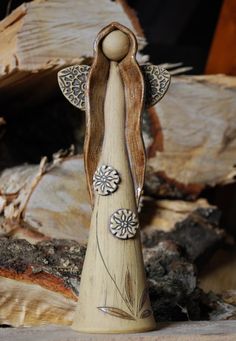 a wooden angel figurine sitting on top of a pile of wood