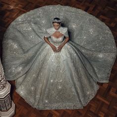 a woman in a white dress is laying on the floor with a large silver blanket over her head