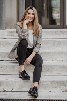 a woman is sitting on the steps smiling and looking at the camera while wearing black shoes