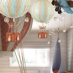 several hot air balloons are hanging from the ceiling in a room with white walls and wood flooring