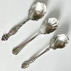 three silver spoons sitting next to each other on a white surface