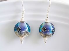 Beautiful under the sea at midnight artisan lampwork puffed beads are combined with sterling silver accents and earwires. Has shades of aqua blue, cobalt bluel, silver and tan. Approx. length is 1-1/4 inches. Ocean-inspired Blue Earrings With Ear Wire, Artistic Blue Round Earrings, Unique Blue Sterling Silver Earrings, Ocean-inspired Blue Earrings For Gifts, Handmade Blue Ocean-inspired Earrings, Artistic Blue Czech Glass Jewelry, Artistic Blue Sterling Silver Earrings, Blue Round Bead Sterling Silver Earrings, Blue Sterling Silver Round Bead Earrings