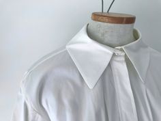 "Vintage Yves Saint Laurent Rive Gauche line button up collared white cotton blend blouse with attractive detailing on cuffs and pleated tie front. Made in Italy. Good condition, small seam hole on shoulder. No marked size, suggested medium. Measurements lying flat: Bust: 15\" Shoulder to cuff: 26\" Length: 26\" Waist: 16\"" White Lapel Collar Blouse With Placket, White Blouse With Lapel Collar And Placket, White Collared Blouse With Placket, White Fitted Blouse With Lapel Collar, White Blouse With Collared Neckline And Placket, Fitted White Blouse With Lapel Collar, White Blouse With Buttons And Lapel Collar, White Blouse With Lapel Collar And Buttons, White Blouse With Button Cuffs And Collared Neckline