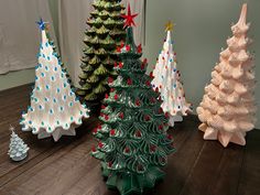 three ceramic christmas trees sitting on top of a wooden table